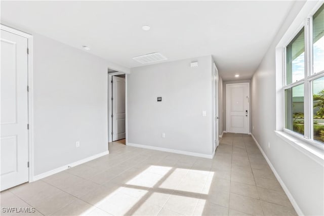 empty room with light tile patterned floors, visible vents, and baseboards