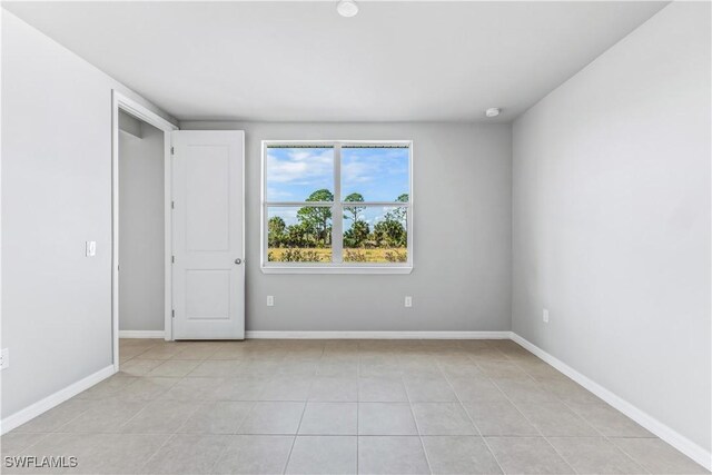 spare room with light tile patterned flooring and baseboards