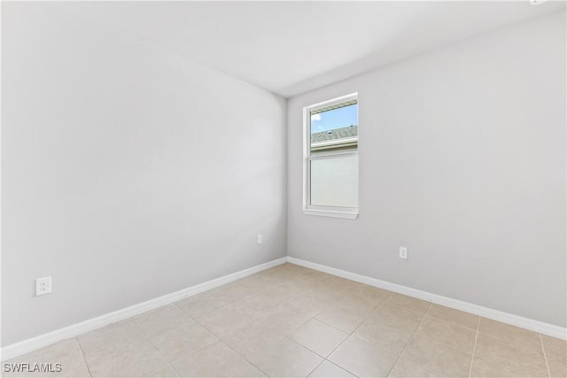 spare room with baseboards and light tile patterned floors