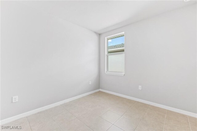 empty room with baseboards and light tile patterned floors
