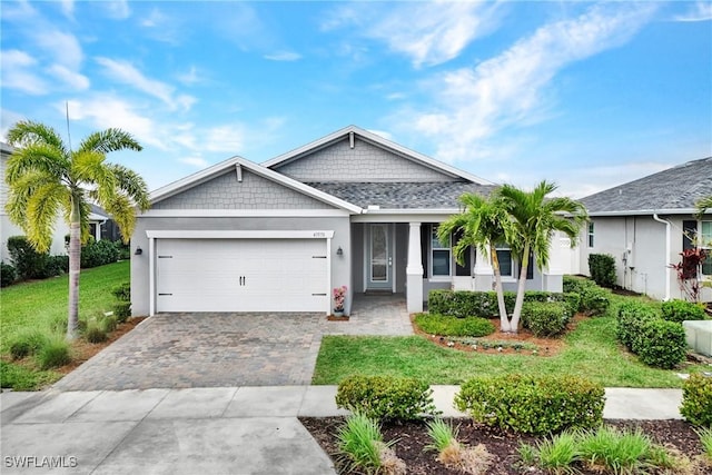 view of front of house featuring a garage, a front lawn, decorative driveway, and stucco siding