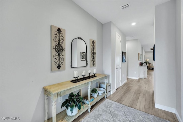 hallway featuring recessed lighting, visible vents, baseboards, and wood finished floors