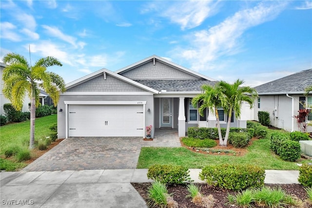 view of front of house featuring a garage, a front yard, decorative driveway, and stucco siding