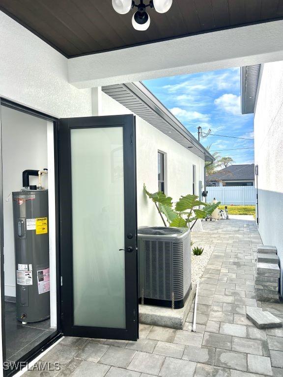 exterior space with water heater, ceiling fan, cooling unit, and fence