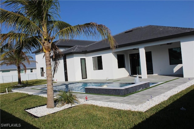 rear view of property featuring a patio, a yard, a ceiling fan, and stucco siding