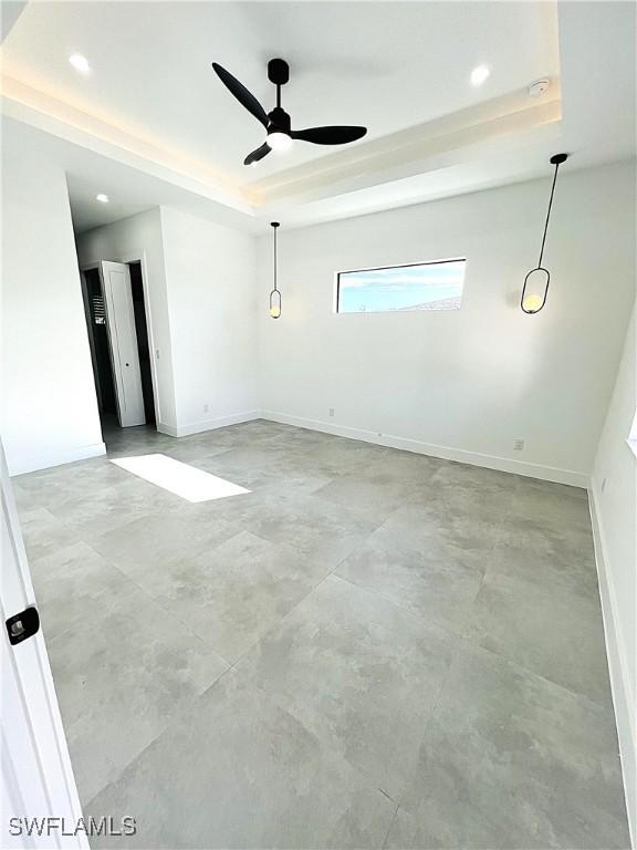 empty room featuring recessed lighting, a raised ceiling, ceiling fan, and baseboards