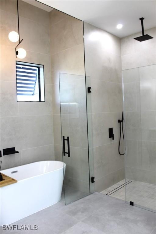 full bathroom featuring a freestanding tub, tile walls, and a shower stall