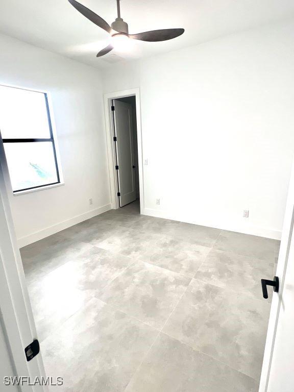 unfurnished room featuring a ceiling fan and baseboards