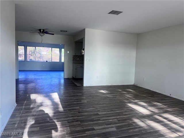 unfurnished room with visible vents, dark wood finished floors, baseboards, and ceiling fan