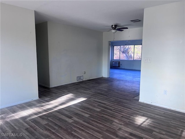 spare room with an AC wall unit, visible vents, dark wood finished floors, and ceiling fan