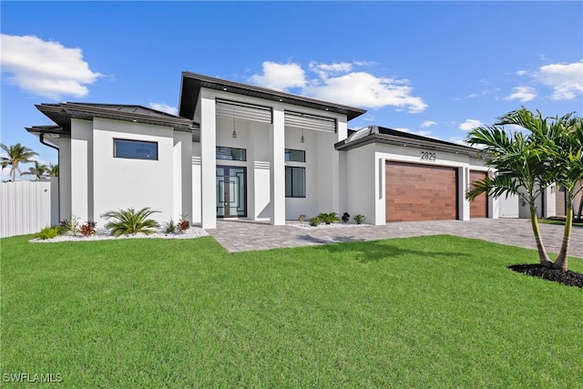 view of front of house with a front yard, fence, an attached garage, and stucco siding