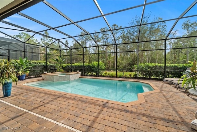 view of swimming pool featuring a patio area, a pool with connected hot tub, and glass enclosure