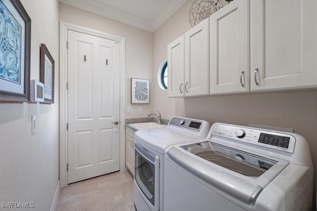 laundry area featuring a sink, washing machine and dryer, cabinet space, and crown molding