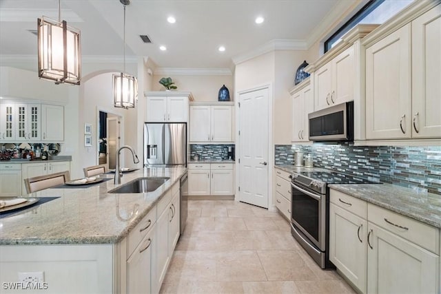 kitchen featuring a sink, ornamental molding, appliances with stainless steel finishes, backsplash, and decorative light fixtures