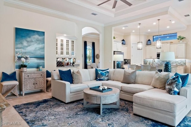 living room with light tile patterned flooring, recessed lighting, visible vents, ornamental molding, and a raised ceiling