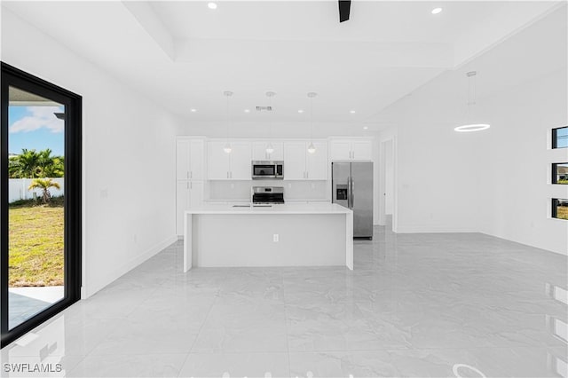 kitchen featuring decorative light fixtures, a center island with sink, light countertops, appliances with stainless steel finishes, and white cabinetry