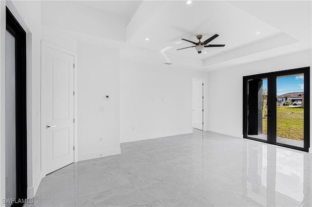 unfurnished room with marble finish floor, a tray ceiling, recessed lighting, and baseboards