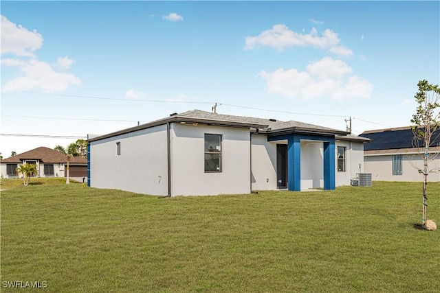 back of house featuring central air condition unit, a yard, and stucco siding