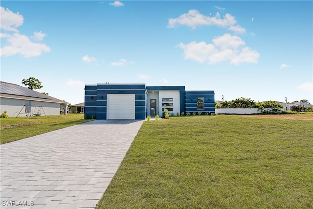 modern home featuring a garage, a front lawn, and decorative driveway