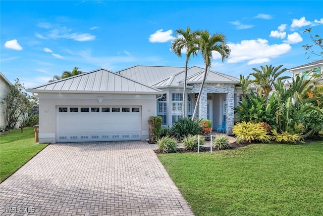 ranch-style home with metal roof, an attached garage, decorative driveway, a front lawn, and a standing seam roof