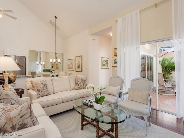 living area featuring high vaulted ceiling, ceiling fan with notable chandelier, visible vents, and wood finished floors