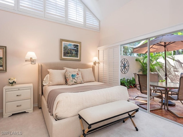 bedroom with access to outside, high vaulted ceiling, and light colored carpet