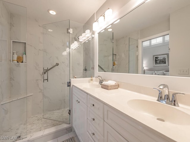 bathroom featuring a sink, a marble finish shower, and double vanity