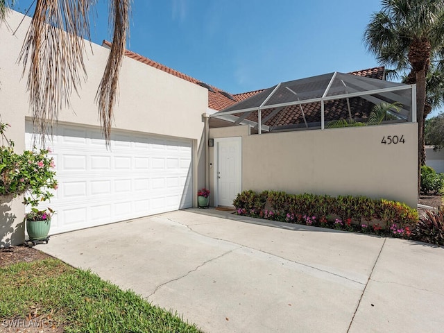 exterior space featuring driveway, glass enclosure, an attached garage, and stucco siding