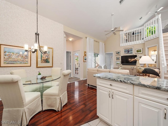 kitchen with open floor plan, decorative light fixtures, light stone countertops, white cabinetry, and ceiling fan with notable chandelier