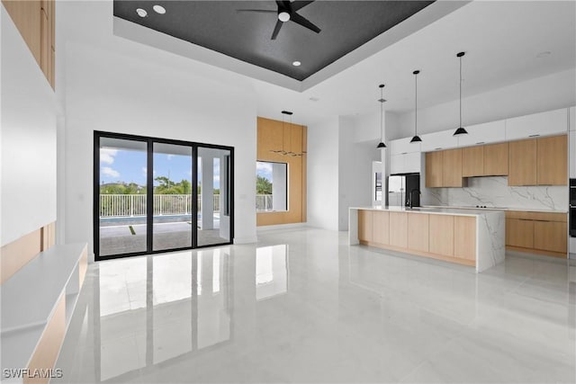 kitchen with light countertops, hanging light fixtures, freestanding refrigerator, a tray ceiling, and modern cabinets