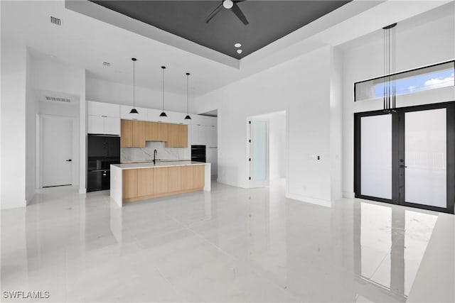 kitchen with white cabinets, light countertops, modern cabinets, a center island with sink, and pendant lighting