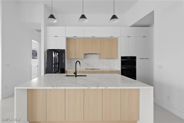 kitchen with hanging light fixtures, modern cabinets, a center island with sink, and white cabinets