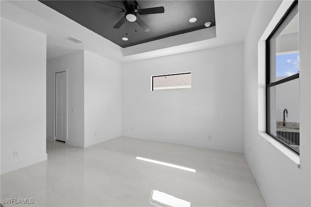 empty room with recessed lighting, a raised ceiling, a healthy amount of sunlight, and visible vents