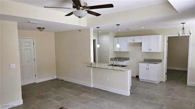 1125 Copley St E, Lehigh Acres, FL 33974 - kitchen with a sink, light stone countertops, a ceiling fan, white cabinetry, and a peninsula