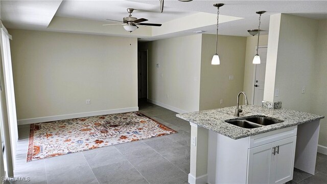 1125 Copley St E, Lehigh Acres, FL 33974 - kitchen featuring a sink, baseboards, a ceiling fan, white cabinets, and pendant lighting