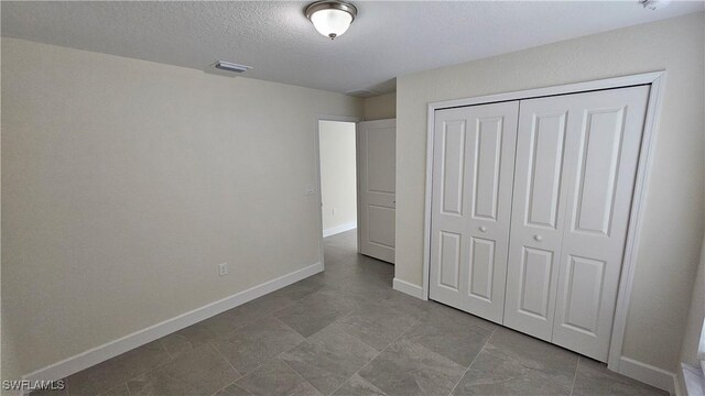 1125 Copley St E, Lehigh Acres, FL 33974 - unfurnished bedroom with baseboards, a closet, and a textured ceiling