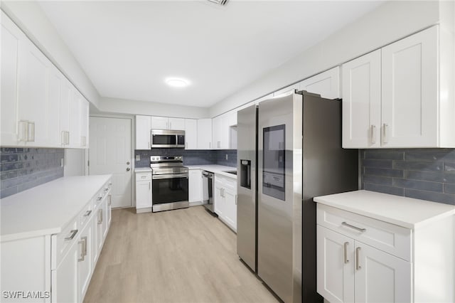 kitchen featuring stainless steel appliances, light wood-type flooring, light countertops, and decorative backsplash