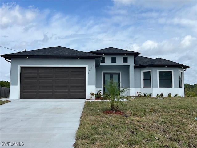 prairie-style house featuring an attached garage, stucco siding, concrete driveway, and a front yard