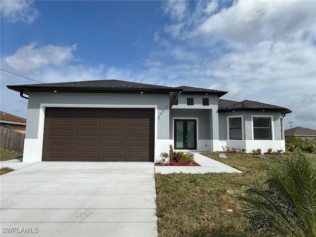 prairie-style house featuring a garage, driveway, french doors, and stucco siding