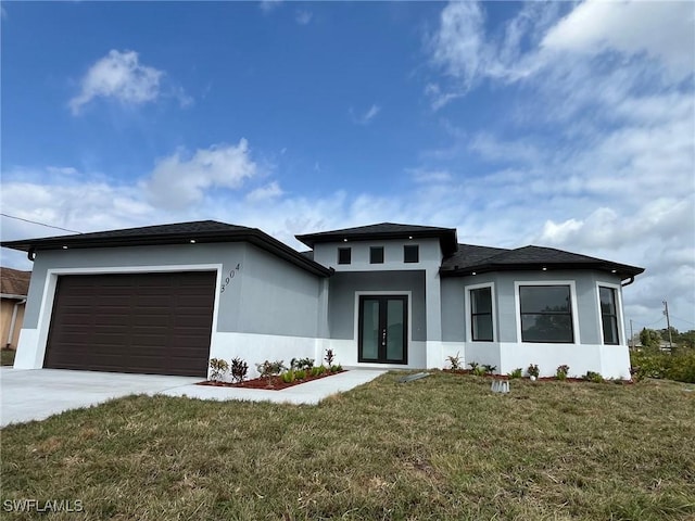 prairie-style house with a garage, driveway, french doors, stucco siding, and a front yard