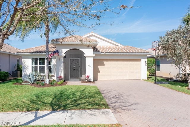 single story home featuring a garage, a tile roof, decorative driveway, stucco siding, and a front yard