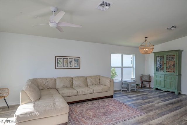 living area with ceiling fan with notable chandelier, wood finished floors, visible vents, and baseboards