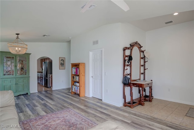 interior space featuring light wood-type flooring, visible vents, vaulted ceiling, and arched walkways