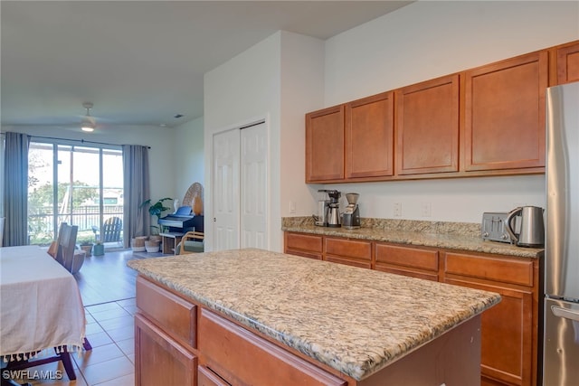 kitchen with brown cabinetry, a kitchen island, open floor plan, and freestanding refrigerator