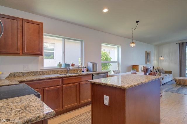 kitchen featuring a sink, a kitchen island, decorative light fixtures, and light stone countertops