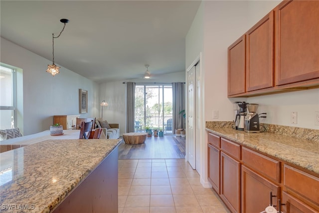 kitchen featuring open floor plan, light stone counters, light tile patterned floors, and pendant lighting