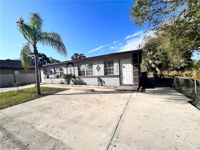 view of front of property with concrete driveway, fence, and stucco siding