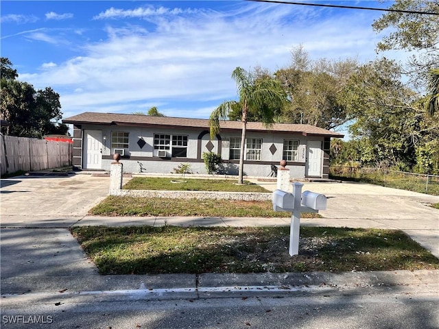 ranch-style home with driveway, a fenced front yard, and stucco siding