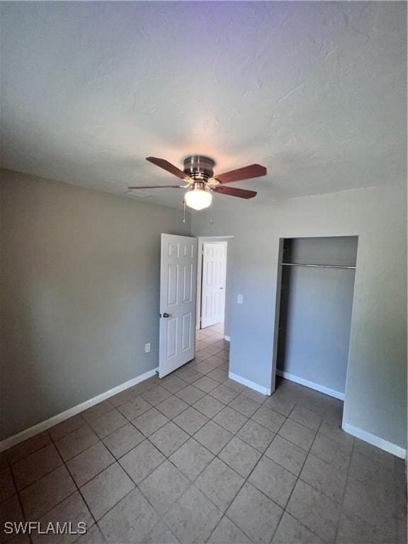 unfurnished bedroom featuring ceiling fan, baseboards, a closet, and light tile patterned flooring