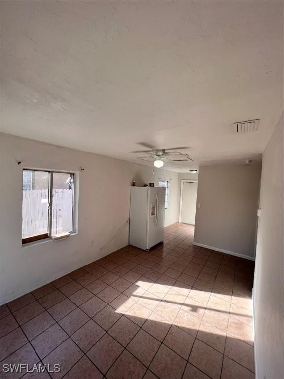 empty room featuring light tile patterned flooring, visible vents, and a ceiling fan